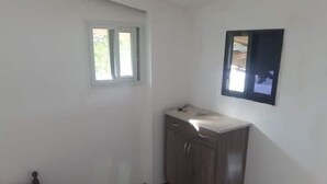 Una habitación pequeña y poco amoblada con un armario de madera, una ventana pequeña y un cuadro en la pared.