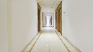 Ein langer, schmaler Hotelgang mit weißen Wänden und Fliesenboden.