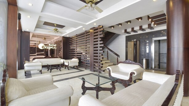 Eine Hotelhalle im modernen Stil, mit einer Sitzecke, Sofas, Sesseln, einem Glastisch, einer Treppe und einem Deckenventilator.