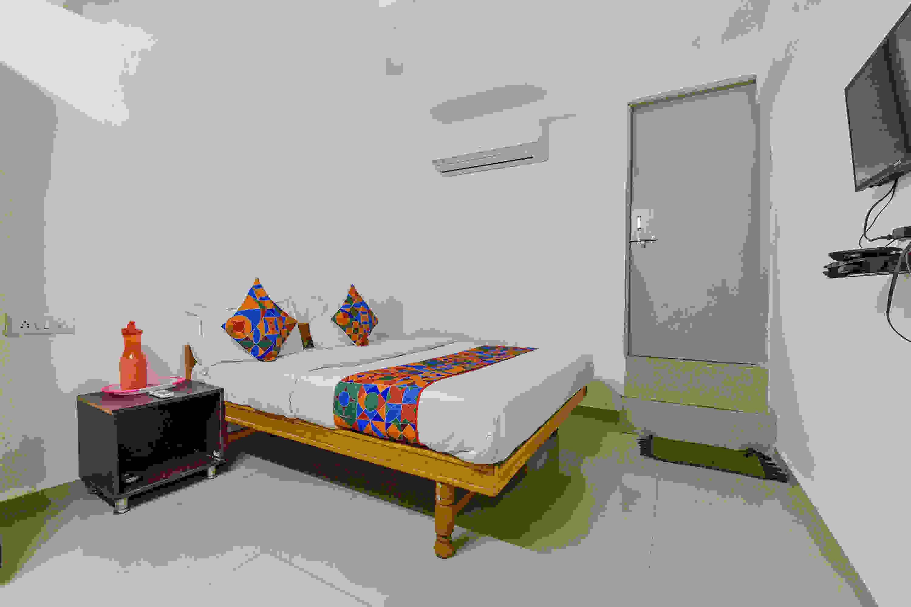 A bedroom with a bed, a nightstand, a door, and a television.