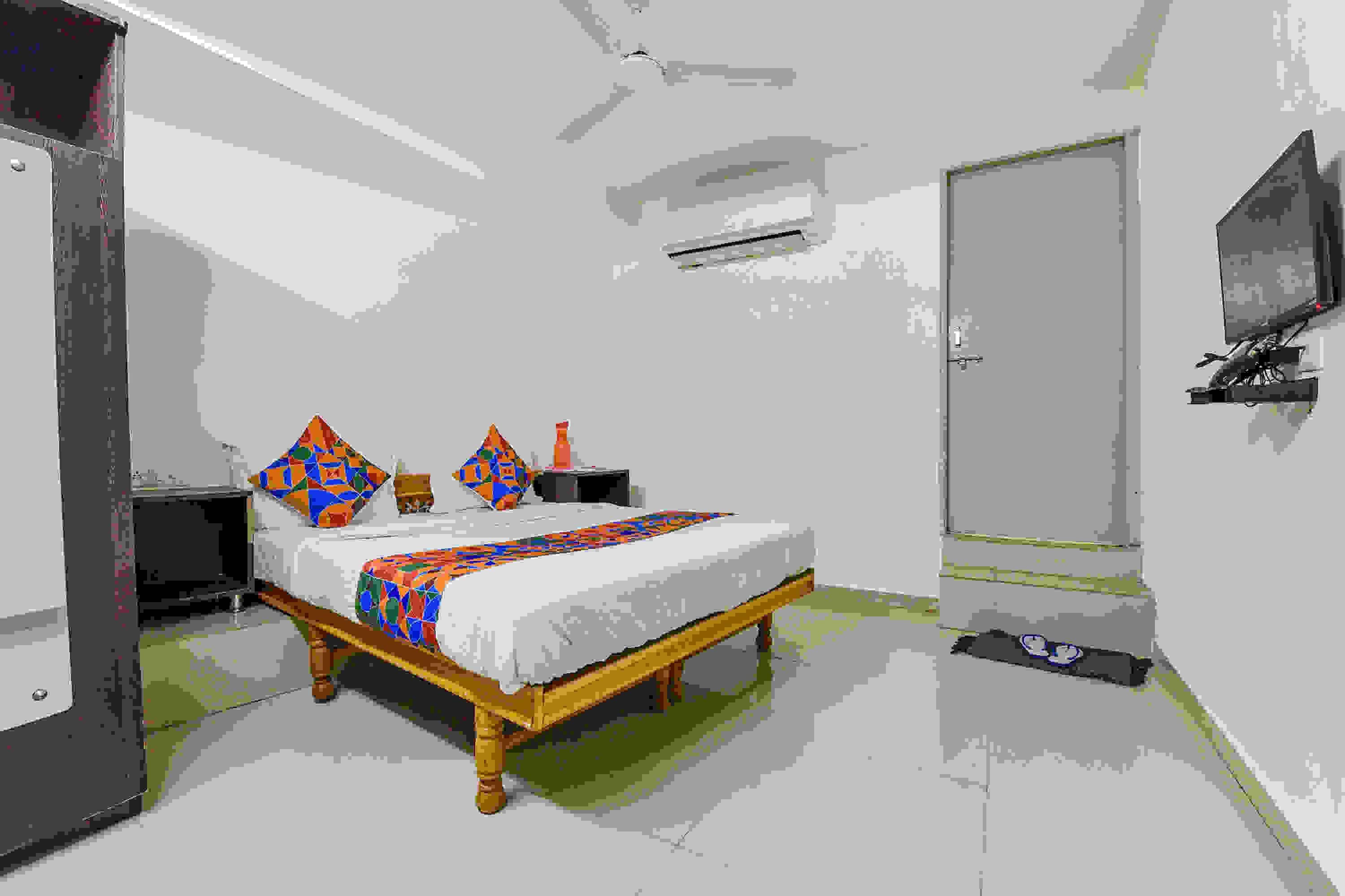 Un dormitorio con cama, mesitas de noche, televisión y una puerta.