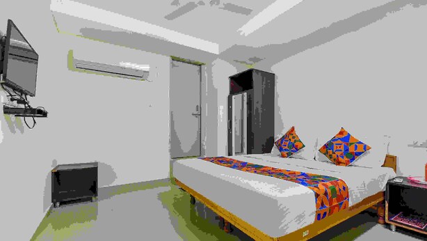 A bedroom with a bed, a television, an air conditioning unit, and a door. - FabExpress Himalaya Inn - Inside Himalaya Mall (Ahmedabad)