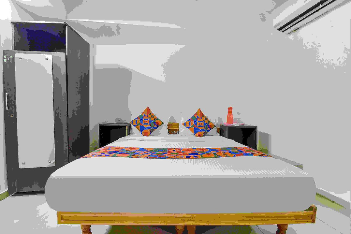 A bed with a colorful quilt, two decorative pillows, a bedside table, and a nightstand.