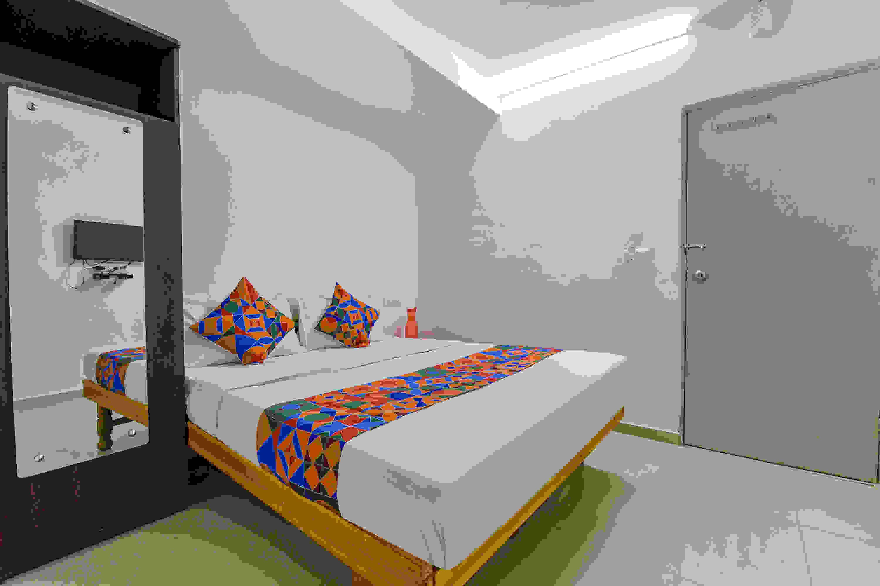 Een slaapkamer met een bed, kussens, een nachtkastje en een deur.