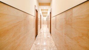 A long, narrow hallway with marble floors and wooden doors, leading to multiple rooms. - Fabhotel Shree Khatu Shyam Palace (Indore)