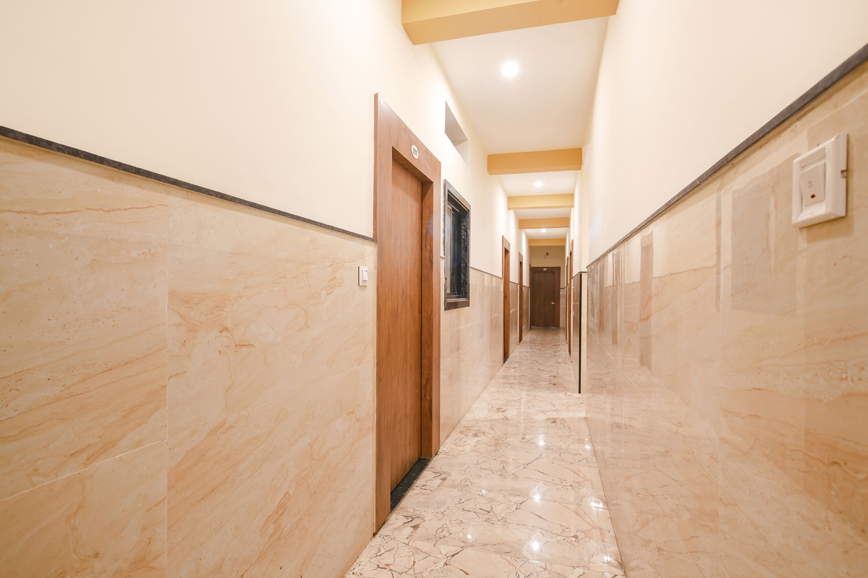 A corridor with marble flooring and wooden doors, leading to multiple rooms.