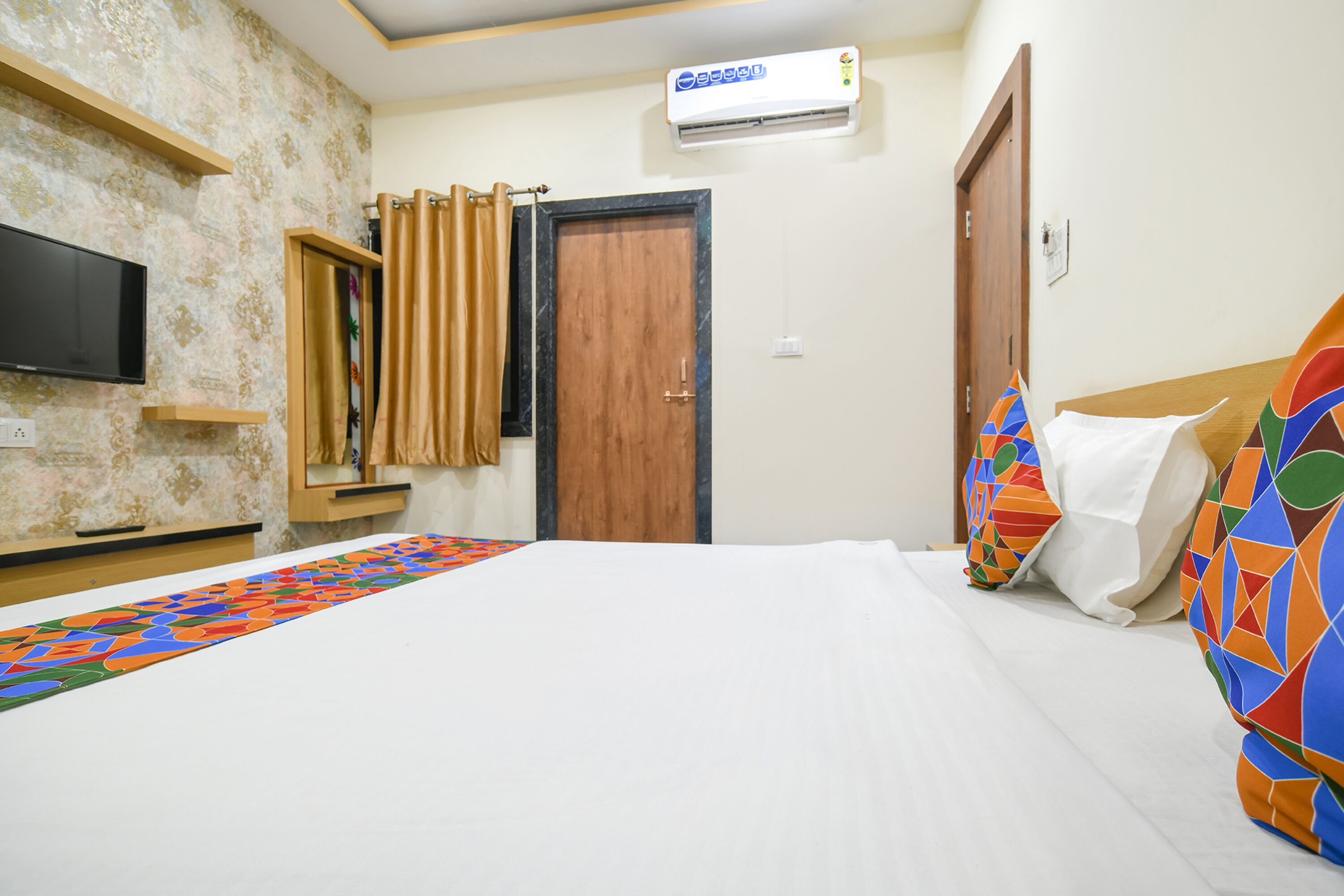 Una habitación de hotel con cama, televisión, aire acondicionado y cortina de ducha.