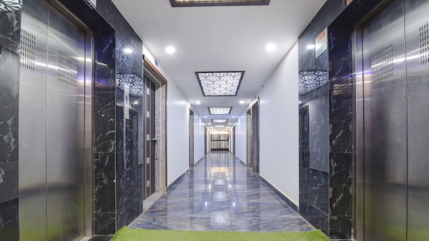 A modern hallway with elevators, marble flooring, and a green carpet. - Fabhotel Maan Palace (Ahmedabad)