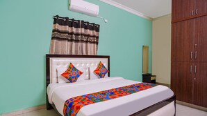A neatly made bed with a colorful bedspread, a headboard, and a curtain. - Fabexpress D Grand (Hyderabad)