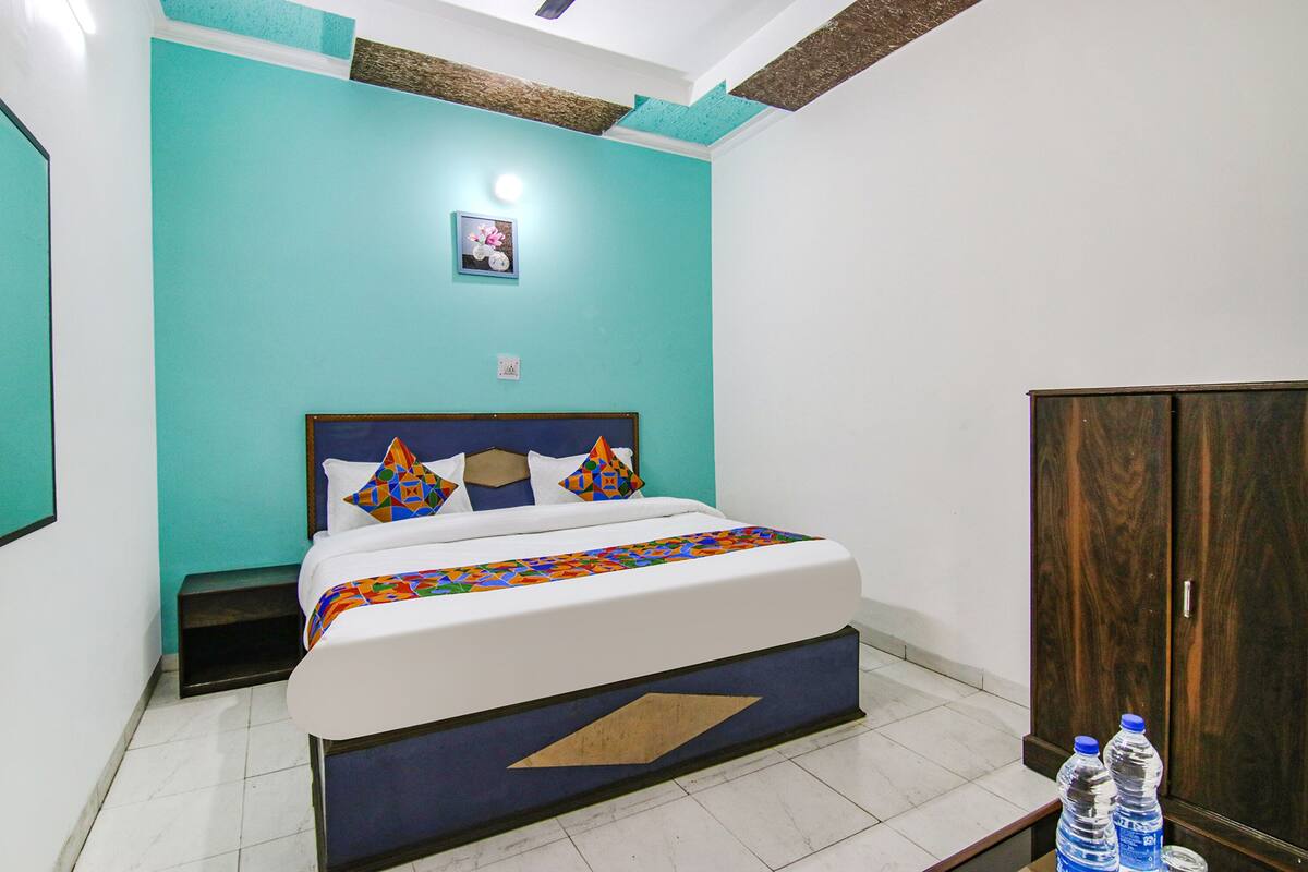 A bedroom with a bed, a nightstand, a wardrobe, and two water bottles on a table.