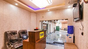 A hotel reception area with a wooden desk, plastic-covered chairs, and a sign reading "fab hotels". - FabHotel Surya Palace 2 (Chandigarh)