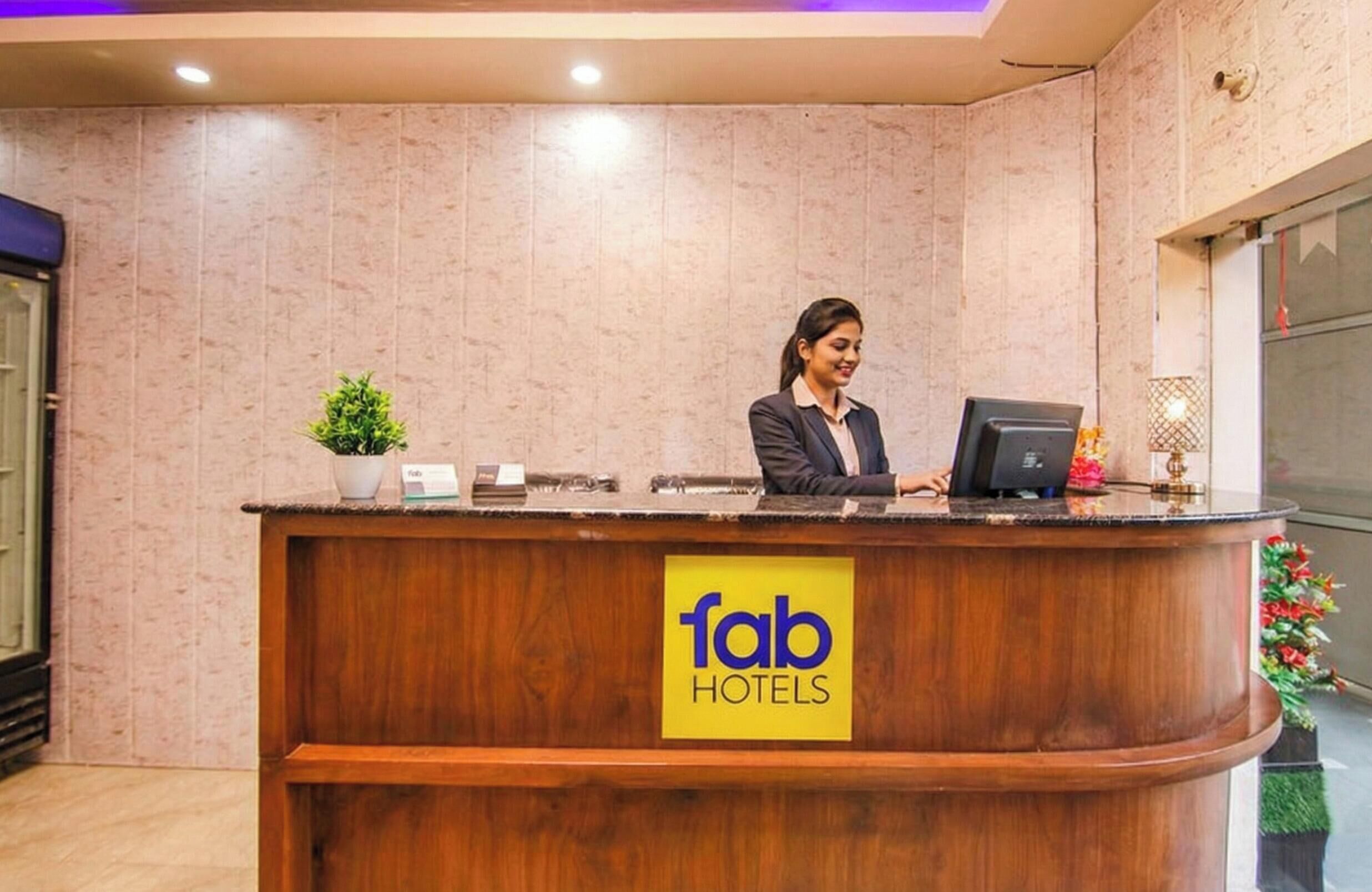 Fab Hotels -hotellin vastaanottotiski on viimeistelty puulla, siinä on pieni ruukkuistutettu kasvi ja kyltti, jossa on hotellin nimi.