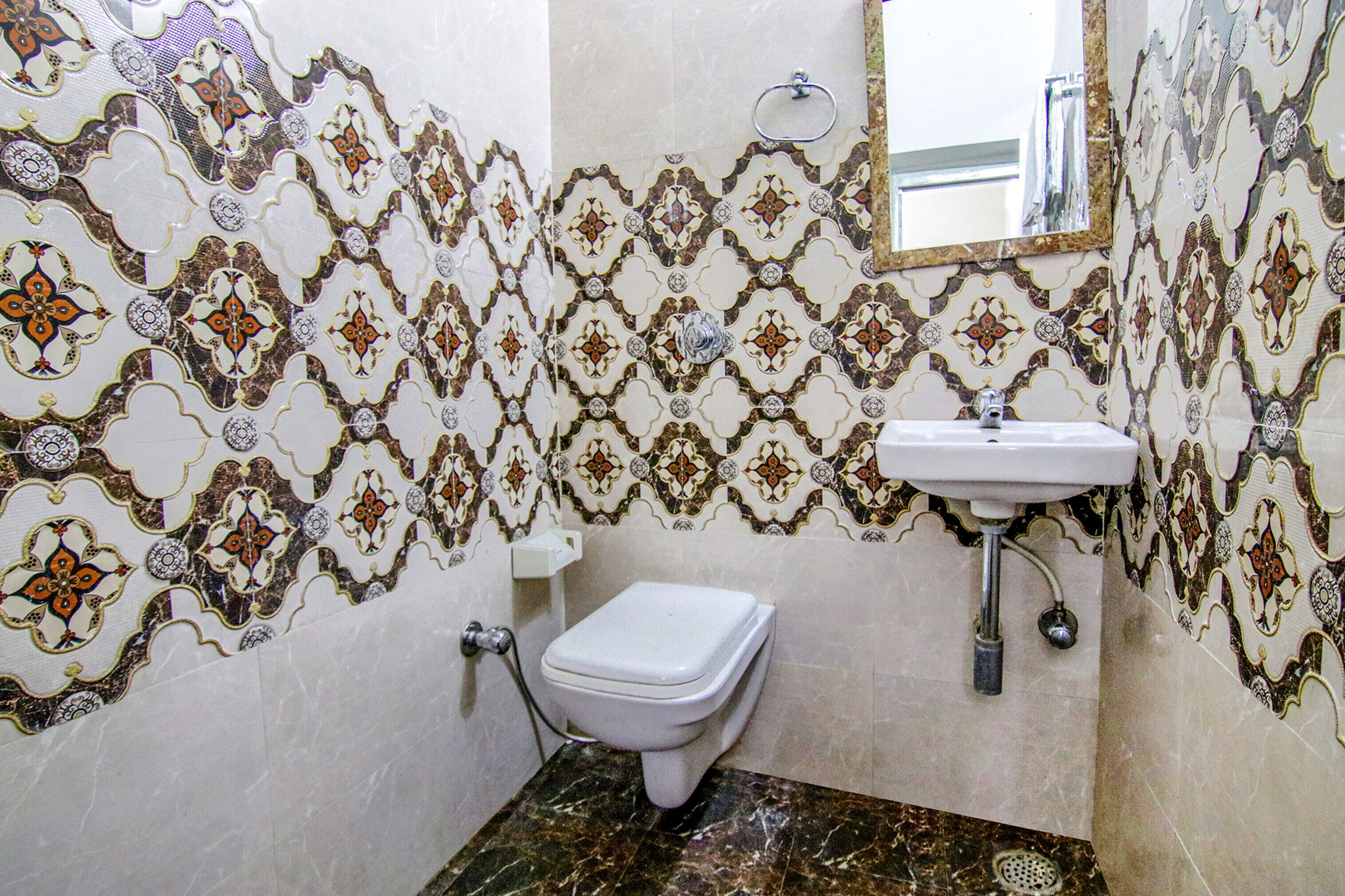 A bathroom with patterned tiles, a toilet, and a sink.