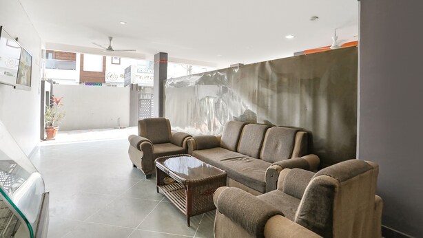 A modern living room with a sectional sofa, a glass coffee table, and a ceiling fan. - Fabhotel Hrg Destiny (Nagpur)