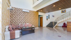 A spacious living area with a sofa set, a coffee table, and a staircase leading to an upper level. - Fabhotel The Avr Grand (Lucknow)