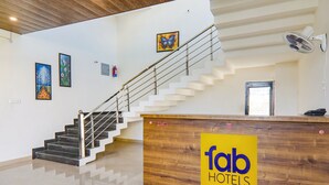 A hotel reception area with a wooden desk, a staircase, and artwork on the walls. - Fabhotel The Avr Grand (Lucknow)