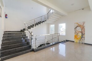 Un intérieur moderne avec un escalier, un extincteur et un grand tableau abstrait.