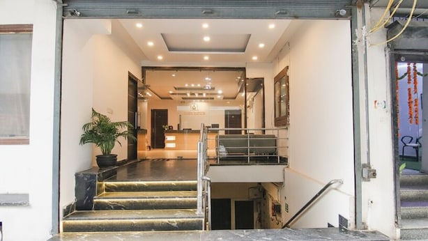 L’entrée d’un hôtel, avec un escalier en marbre, un comptoir d’accueil et une plante en pot.