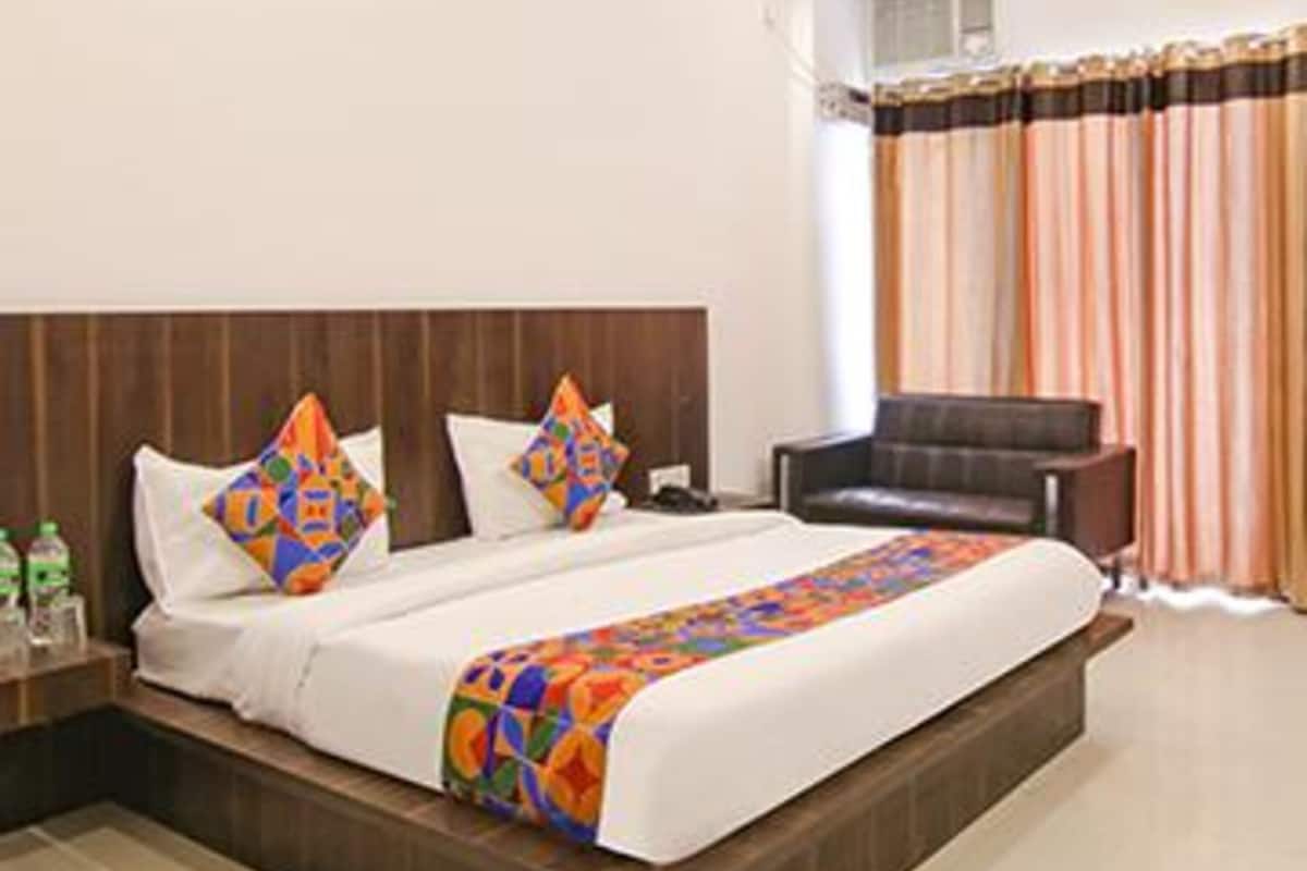 A hotel room with a large bed, a wooden headboard, a desk, and a chair.