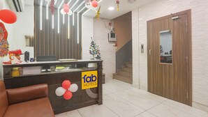 Zona de recepción de hotel con un mostrador de madera, un árbol de Navidad y una escalera que sube a otro piso.