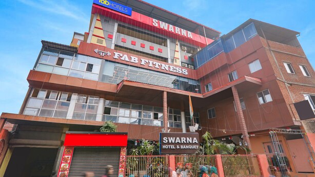Un hotel con un letrero que dice 'Swarna Hotel & Banquet' y 'Fab Fitness'.
