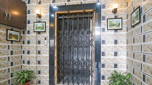 A hotel entrance with a decorative metal gate, patterned wall tiles, and potted plants. - FabHotel Om Sai I (Nashik)