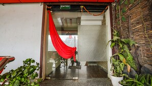 An entrance with a red curtain, a sign reading "ENTRY", and a wooden wall with plants. - Fabhotel Leaf Paradise (Lucknow)