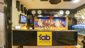 A reception desk with clocks, a TV, and a large horse painting. - Fabhotel Leaf Paradise (Lucknow)