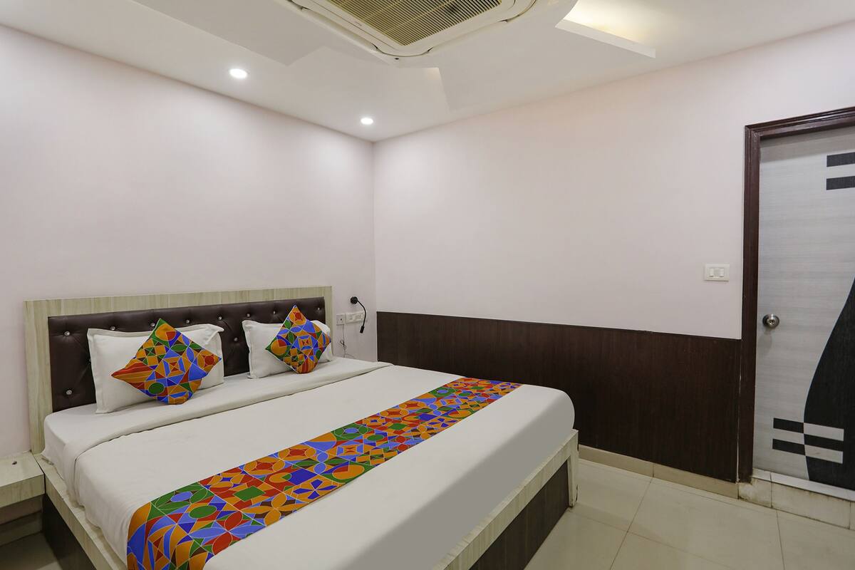 A neatly made bed with a patterned bedspread, a headboard, and two decorative pillows.