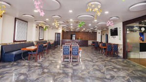 A spacious restaurant with a marble floor, multiple seating areas including booths and tables, and decorative ceiling elements. - Fabhotel Leaf Paradise (Lucknow)