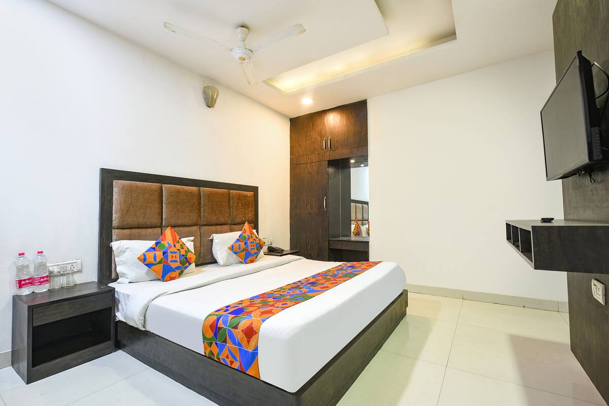 A hotel room with a bed, a nightstand, a TV mounted on the wall, and a ceiling fan.