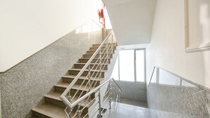 A staircase with metal railings and granite steps, leading to a landing with a window. - FabHotel Belwood (New Delhi)