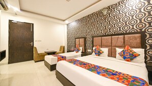 A hotel room with a large bed, two bedside tables, a chair, and a patterned wall. - FabHotel Belwood (New Delhi)
