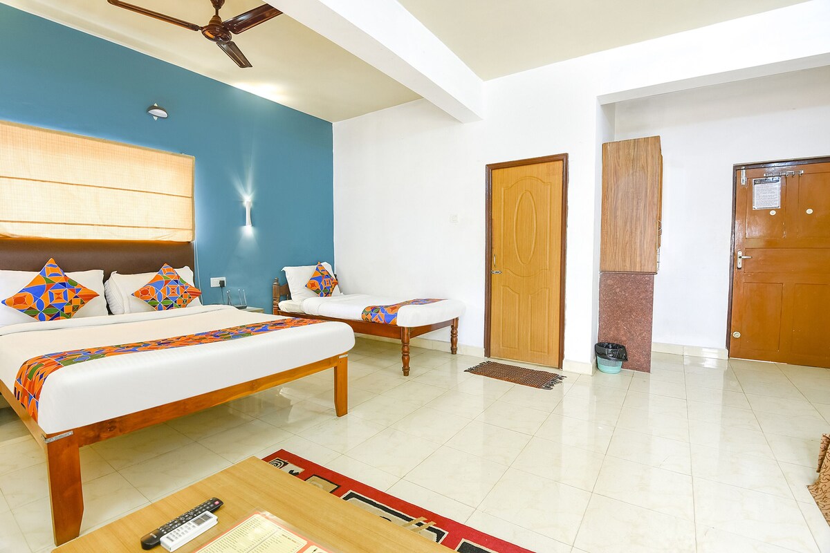 A hotel room with a large bed, a smaller bed, a desk, and a ceiling fan.