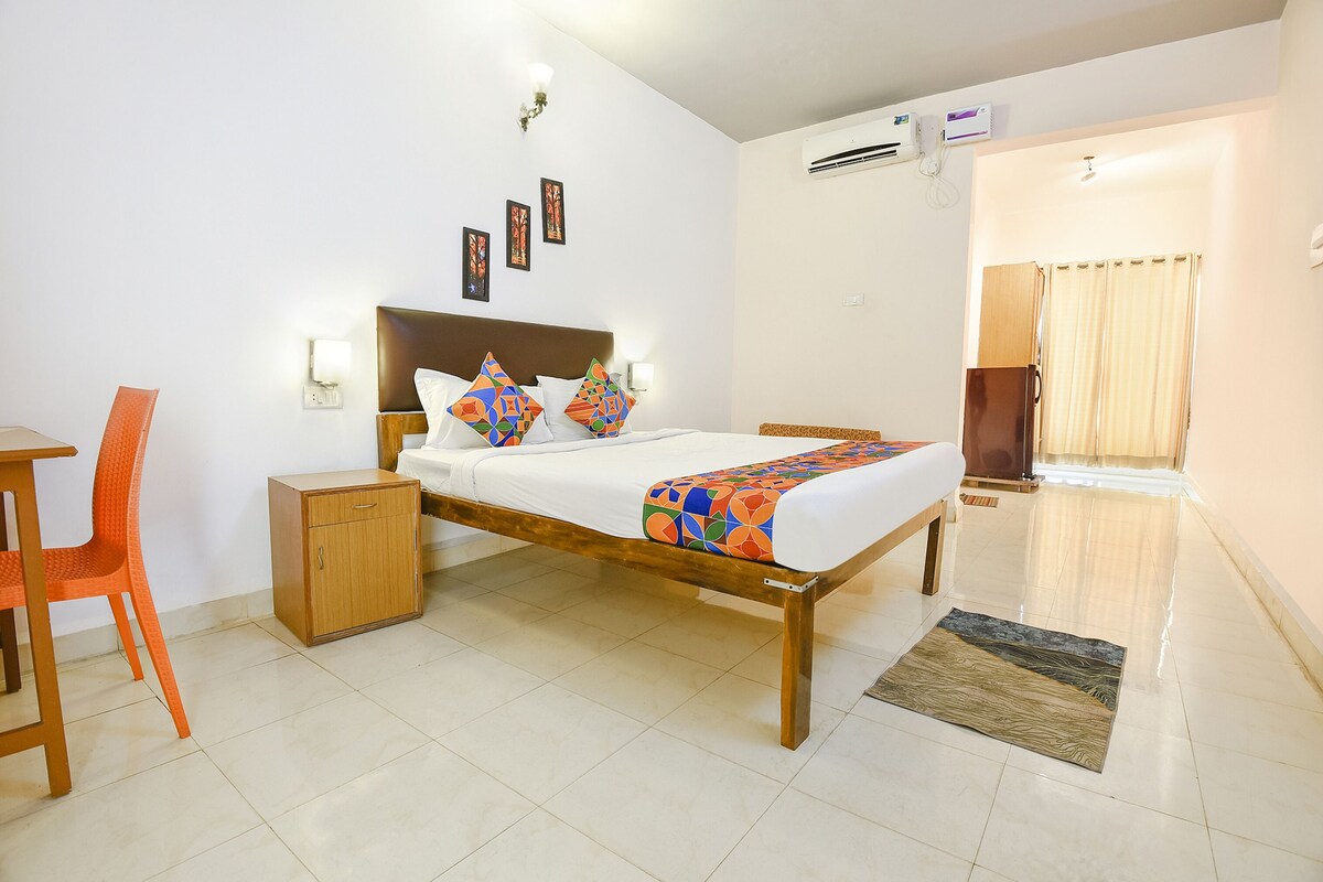 A neatly arranged hotel room with a bed, bedside tables, a chair, and a small cabinet.