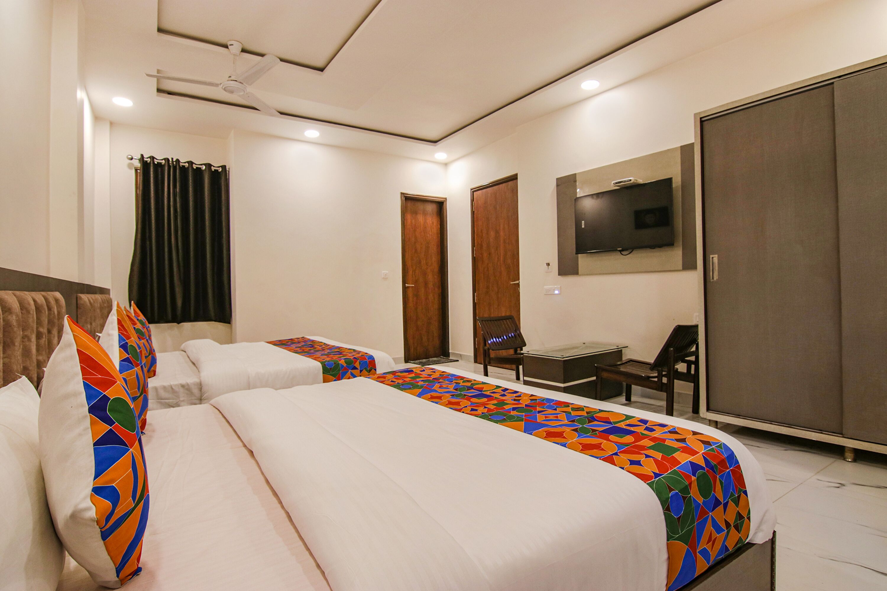 Habitación de hotel con dos camas, un escritorio, una silla, un televisor y un armario.