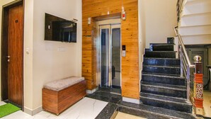 A modern interior with a wooden wall, a bench, a staircase, and a door. - Fabhotel Aryan Grand (Amritsar)