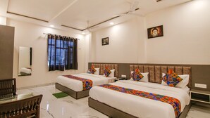 A hotel room with two beds, a ceiling fan, a window with curtains, a small table, and a chair. - Fabhotel Aryan Grand (Amritsar)