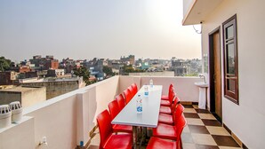A balcony with a checkered floor, a table with red chairs, and two water bottles. - Fabhotel Aryan Grand (Amritsar)