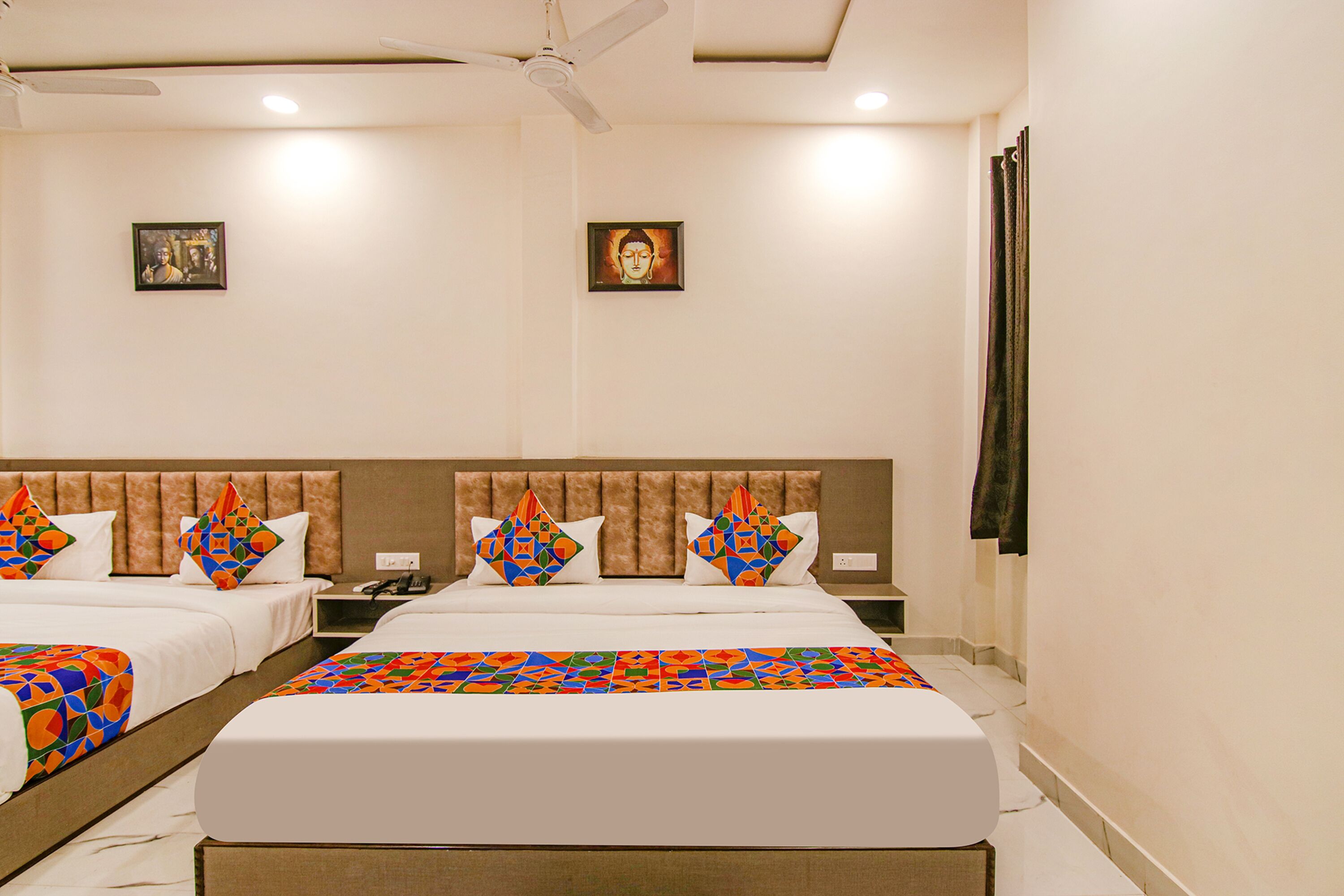 A hotel room with two beds, a headboard, a ceiling fan, and two framed pictures on the wall.