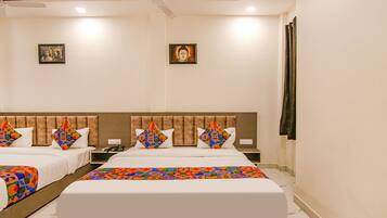 A hotel room with two beds, a headboard, a ceiling fan, and two framed pictures on the wall.