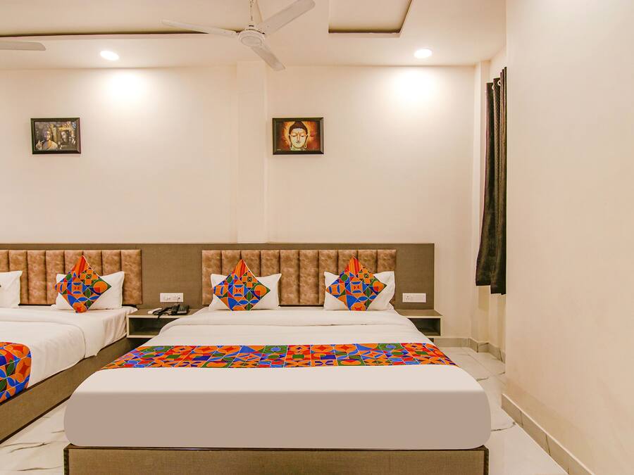 A hotel room with two beds, a headboard, a ceiling fan, and two framed pictures on the wall.
