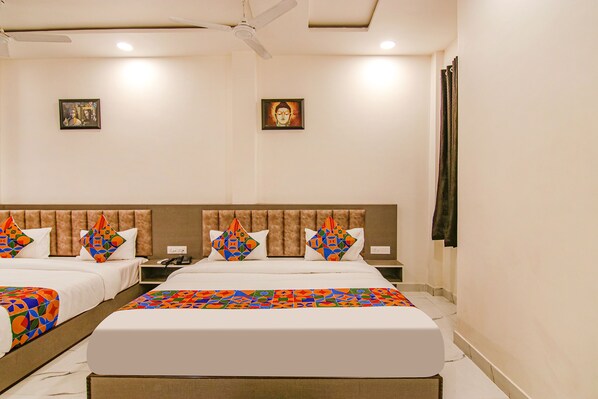 A hotel room with two beds, a headboard, a ceiling fan, and two framed pictures on the wall.
