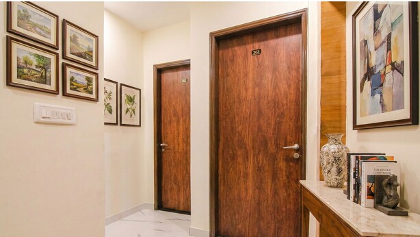A hallway with wooden doors, numbered 303, and framed landscape paintings on the wall. - Fabhotel Aryan Grand (Amritsar)