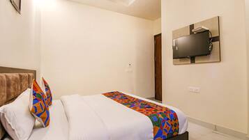 A hotel room with a bed, a TV mounted on the wall, and a door.
