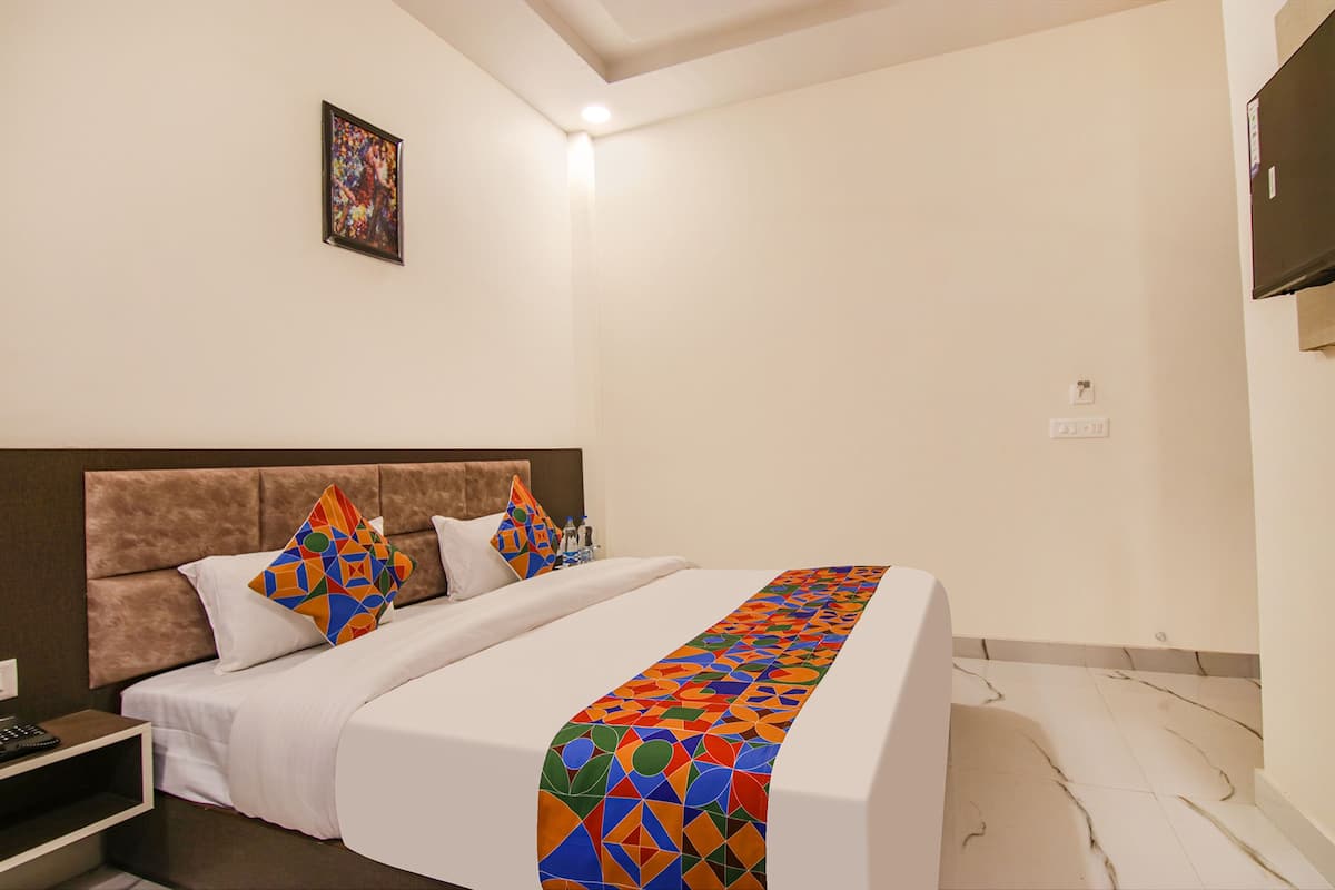 A hotel room with a large bed, a headboard, and a single wall-mounted TV.