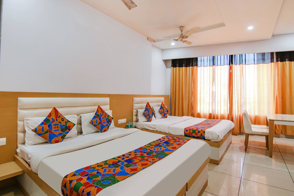 A hotel room with two beds, a ceiling fan, and a table.
