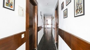 A hallway with wooden paneling and black flooring, leading to a room with a door. - FabExpress The Premium Villa (New Delhi)
