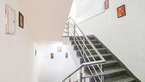 A staircase with metal railings and a handrail, leading to a landing with a door and a small window. - FabExpress The Premium Villa (New Delhi)