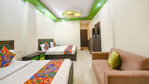 A hotel room with two beds, a sofa, a ceiling fan, and a TV. - Fabhotel Kempty Lake Resort (Dhanaulti)